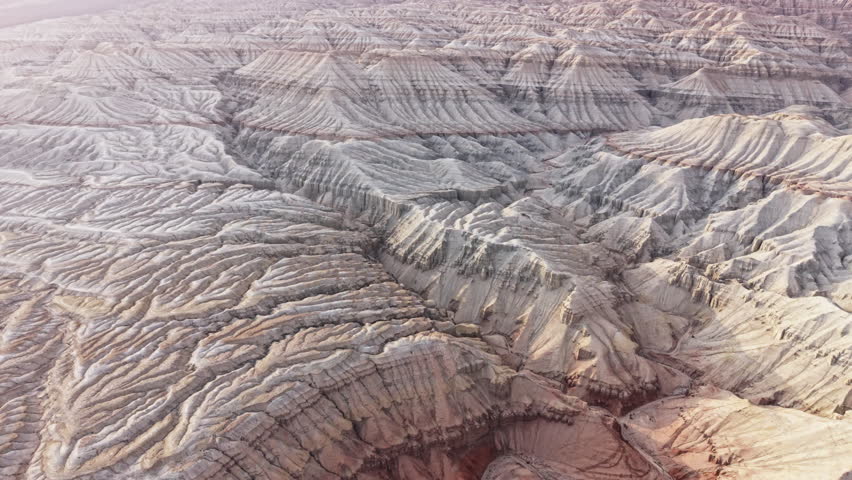 Aerial view of white brown striped layered sedimentary mountains and unique geological pattern in Altyn Emel national park, Kazakhstan