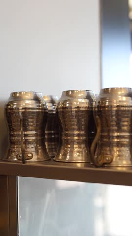 Traditional metal cups being arranged by hand, highlighting authentic craftsmanship, polished texture, and the cultural aesthetic of traditional drinkware.