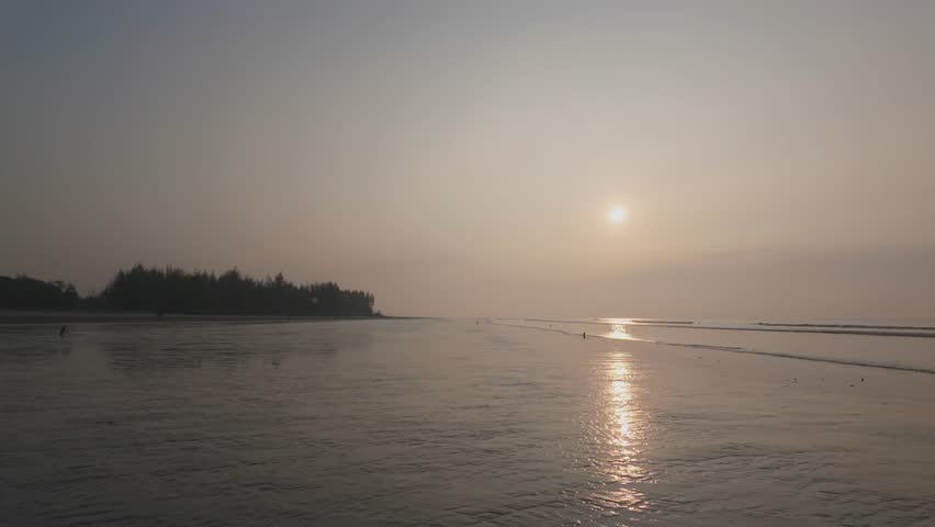 Beautiful sunrise scene over a calm sea with warm sunlight reflecting on gentle ocean waves. The morning sky glows softly as the sun rises above the horizon .