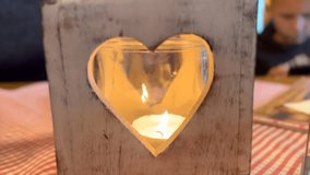 Wooden heart-shaped candle holder with a flickering tealight inside creating a romantic atmosphere - Powered by Shutterstock - Get 15% off with code: PIKWIZARD15
