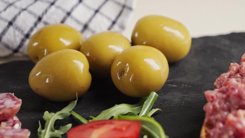 Snack plate beef tartar, cherry tomatoes, green olives and fuet sausage, jamon. Wine snack. High quality 4k footage
