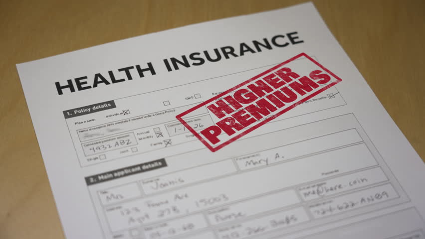 Health insurance form stamped “HIGHER PREMIUMS” in red, symbolizing rising costs after the end of ACA subsidy credits in 2025. Fictional data on form. 14941  	