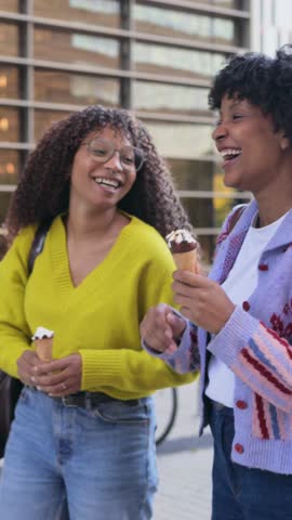 Happy African American women eating ice cream cones outdoors