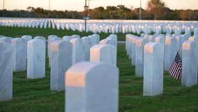 American national military cemetery with rows of white tomb stones and USA flag on green grass lawn. Memorial Day concept. - Powered by Shutterstock - Get 15% off with code: PIKWIZARD15