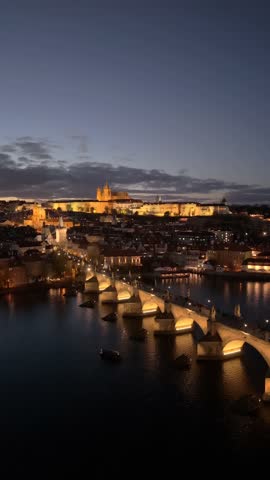 Experience the beauty of Prague at dusk with illuminated landmarks like Prague Castle and Charles Bridge reflecting on the Vltava River as the city transforms into a nighttime wonder.