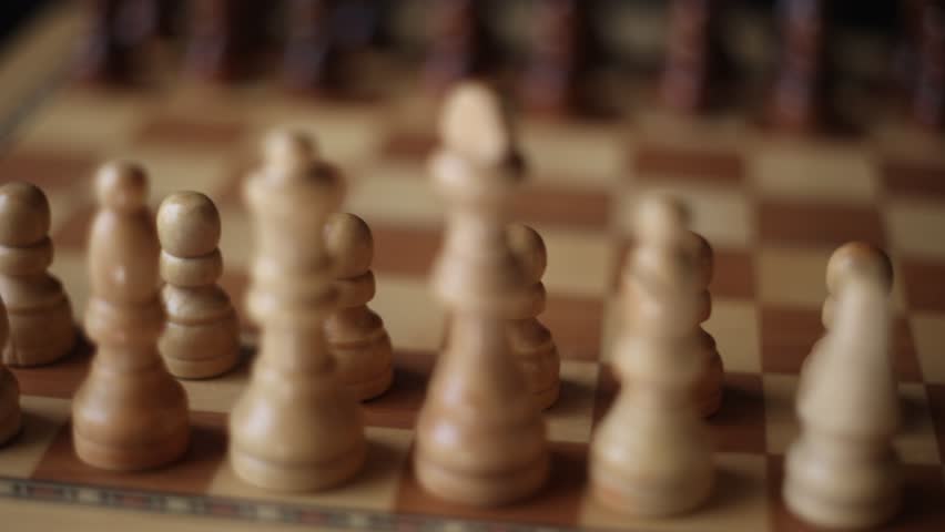 Animated chessboard rotating steadily with chess pieces arranged for play, representing the classic battle between dark and light pieces in intellectual competition