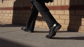 Low angle of a man in a black suit and shoes standing on a sidewalk. The bright sun creates strong shadows, conveying a formal or mysterious mood. Use for business or urban themes. - Powered by Shutterstock - Get 15% off with code: PIKWIZARD15