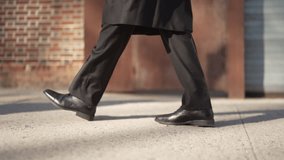 Close-up of a man's legs in black trousers and shoes walking on a city sidewalk. The scene evokes a sense of purpose and urban commute. Ideal for business or lifestyle content. - Powered by Shutterstock - Get 15% off with code: PIKWIZARD15