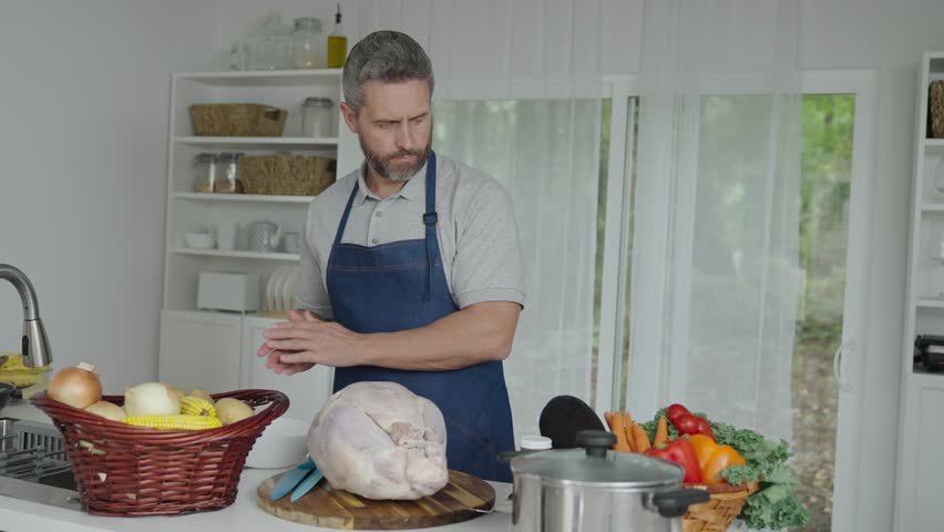 Cooking turkey for Thanksgiving. Mature man in apron with turkey. Home menu. Thanksgiving day dinner. Hispanic man cooking in kitchen. Thanksgiving dinner food. Man cooking food. 4k footage