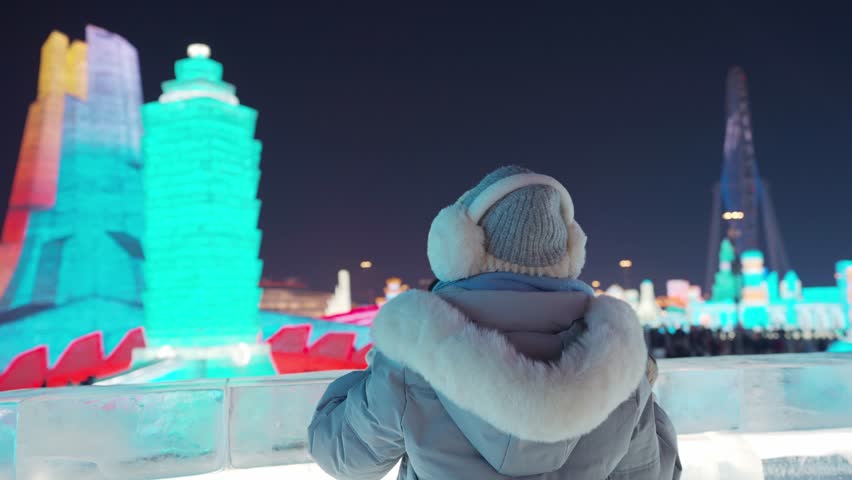 Young happy female tourist enjoying at ice and snow world festival at night in Harbin, China