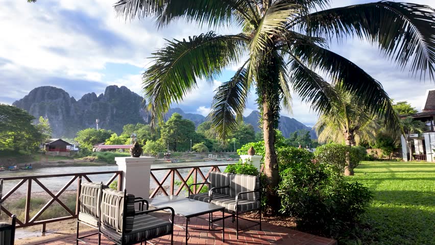 Vang Vieng resort patio overlooking Nam Song River and limestone mountains, offering a relaxing vacation