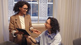 Two colleagues discussing business ideas in a bright modern office using a digital tablet and laptop showing communication cooperation and creative teamwork in professional workplace - Powered by Shutterstock - Get 15% off with code: PIKWIZARD15