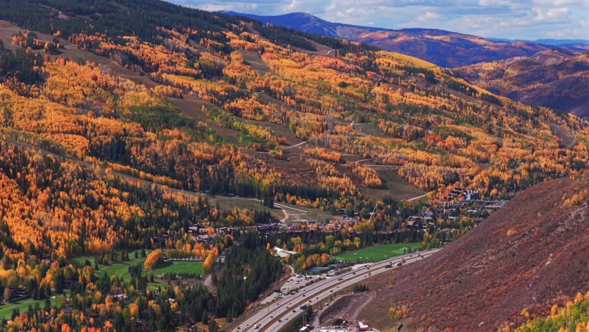 Vail village ski resort small Colorado Rocky Mountains drone aerial fall autumn quaking aspen trees leaf peeping season morning blue skies clouds i70 cars traffic forward pan up motion