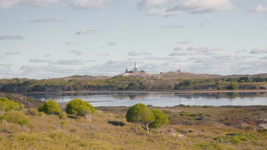 Cinematic 4K footage of Rottnest Island’s landscape on a hot, clear day, panning across empty land with salt lakes, small trees, and distant hills, showcasing the island’s wide open natural beauty.