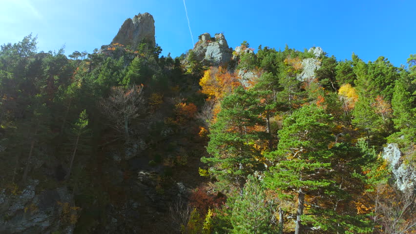 Fpv drone flying in the mountains with red, yellow and green trees in the autumn season.