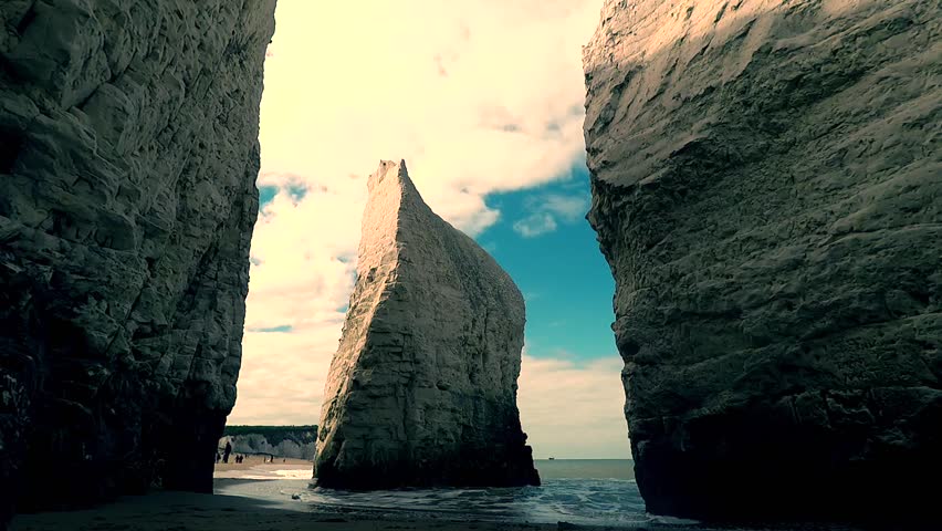 Slow motion footage showing towering chalk cliffs and distinct sea stack at Old Harry Rocks near Swanage in Dorset, England, with calm waves and bright sky creating dramatic coastal scenery.