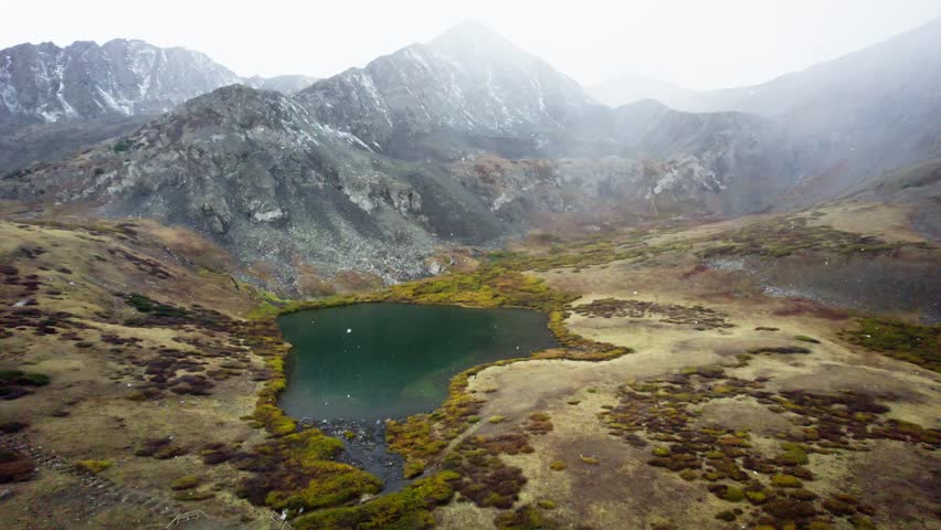 beautiful colorado mountain lake during hail storm with hikers along the mountain trail