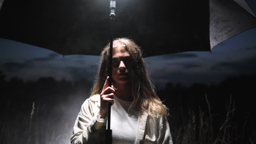 Umbrella woman in a dark field creating a striking artistic moment