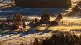 Aerial view of misty fog rolling above frosted snowy farmlands and forests with rustic barns under pale light - Powered by Shutterstock - Get 15% off with code: PIKWIZARD15