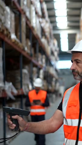 Warehouse team managing inventory with barcode scanner and tablet, inspecting stock on pallets and racks while coordinating logistics and shipments in an industrial storage facility