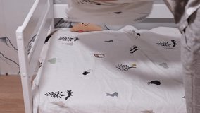 Woman spreads a clean duvet cover over a child’s bed in a nursery room. - Powered by Shutterstock - Get 15% off with code: PIKWIZARD15