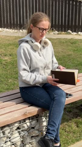 A young woman reading a book on a walk. 