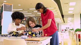 Indian, African, and mixed Asian-Caucasian students collaborate on a robotics project at a library table. Diverse kids engage in teamwork, research, and hands-on STEM learning in a classroom setting. - Powered by Shutterstock - Get 15% off with code: PIKWIZARD15