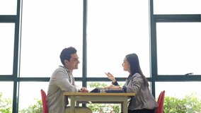 Two people sit in the library across a table by large windows, engaged in a friendly discussion with books on the desk, suggesting study or a meeting in a bright learning space. - Powered by Shutterstock - Get 15% off with code: PIKWIZARD15