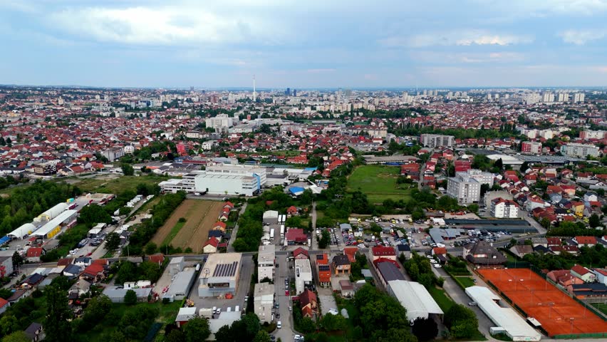 Aerial drone view of Zagreb skyline, Croatia a mix of red rooftops, green areas, and modern buildings stretching toward the horizon under cloudy summer light