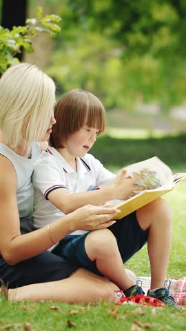 A boy sits in a park with a caregiver deeply engaged in creating colorful art