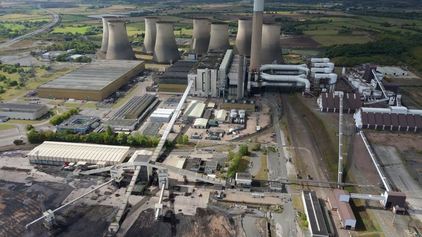 - High altitude drone view of coal power facility with cooling towers and turbulent skies in central England