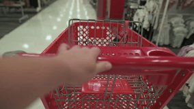 individual pushing red cart through welllit clothing section steadily, person maneuvering red shopping cart along illuminated apparel aisle with deliberate speed and attention to detail - Powered by Shutterstock - Get 15% off with code: PIKWIZARD15