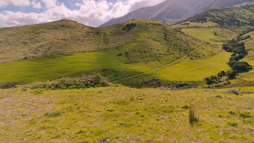 Majestic aerial sweep over rolling green landscapes under blue sky