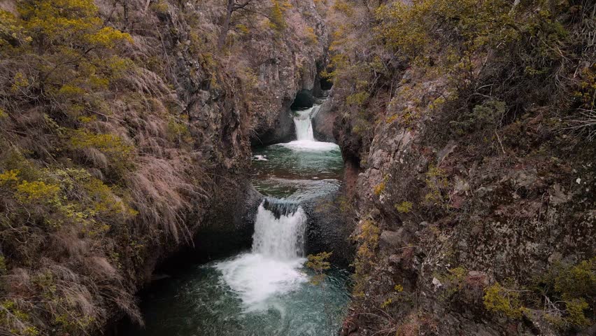 Forward drone aerial of multi-tiered waterfalls with turquoise pools, Siete Tazas National Park, Ñuble, Chile through narrow canyon slot