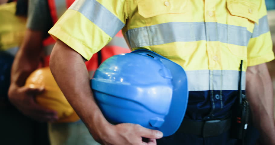 Hands, row and people walk with helmet for safety, warehouse inspection and industry protocol. Line, employees and waiting with hard hat for quality control, workplace compliance and construction ppe