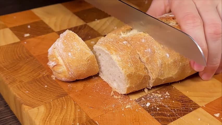 Close-up of hands slicing freshly baked artisan bread on a wooden cutting board for breakfast