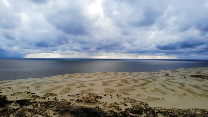 Aerial view of vast sand dunes and a stormy sea
