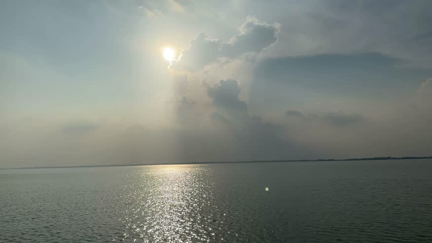 Serene Sunset Over Calm Waters with Dramatic Clouds