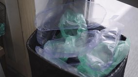 Hand disposing of used plastic shoe covers in trash can, highlighting waste management, hygiene, protection, and environmental impact of disposable personal protective equipment, close-up, slow motion - Powered by Shutterstock - Get 15% off with code: PIKWIZARD15