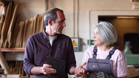 Two senior professional colleagues using a digital tablet for work planning. An experienced male supervisor and a female employee working in a carpentry - Powered by Shutterstock - Get 15% off with code: PIKWIZARD15