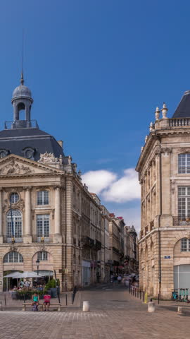 Place de la Bourse timelapse hyperlapse in Bordeaux, France, with restaurants surrounded by classic architecture under a cloudy blue sky. People walking around the main square and central streets