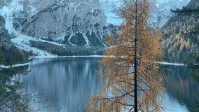 Cinematic view of Lake Braies in the Italian Dolomites with snow-capped mountains and autumn-colored trees. Drone captures serene waters, vibrant fall foliage, and majestic alpine scenery - Powered by Shutterstock - Get 15% off with code: PIKWIZARD15