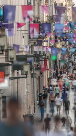 Tourists and locals walking and shopping in Rue Sainte-Catherine timelapse, Bordeaux, France. The longest pedestrian street in the country. Atmosphere of urban life. Colorful flags decorate the street