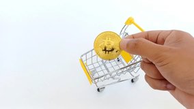 hand inserts token Bitcoin into a small shopping cart symbolizing crypto trading and digital shopping, and digital finance in a modern economy. - Powered by Shutterstock - Get 15% off with code: PIKWIZARD15