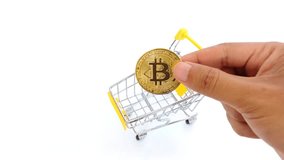 hand inserts token Bitcoin into a small shopping cart symbolizing crypto trading and digital shopping, and digital finance in a modern economy. - Powered by Shutterstock - Get 15% off with code: PIKWIZARD15