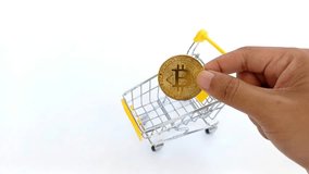 hand inserts token Bitcoin into a small shopping cart symbolizing crypto trading and digital shopping, and digital finance in a modern economy. - Powered by Shutterstock - Get 15% off with code: PIKWIZARD15