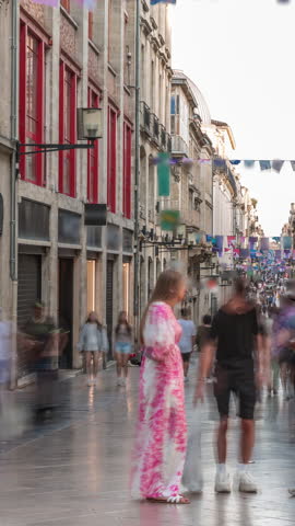 Tourists and locals walking and shopping in Rue Sainte-Catherine timelapse, Bordeaux, France. The longest pedestrian street in the country. Colorful flags decorate the street. Atmosphere of urban life