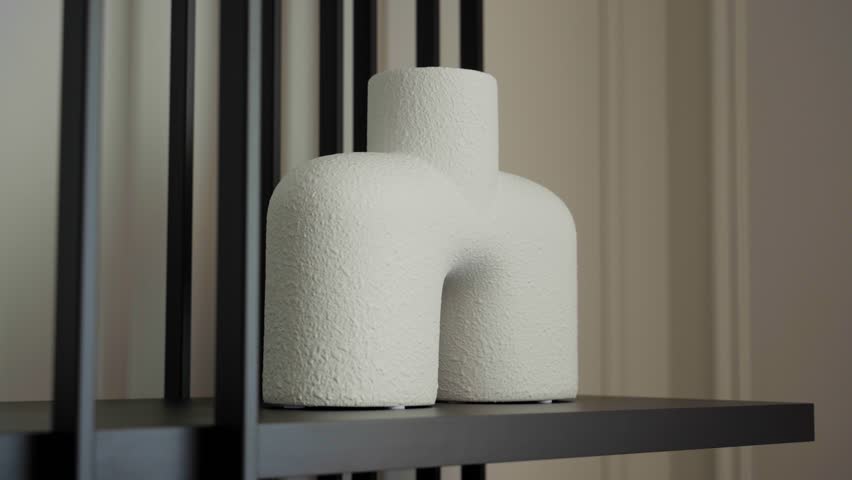 Slow motion shot of modern white decorative vase on black metal shelf, minimalistic home interior design detail with elegant contemporary decor.