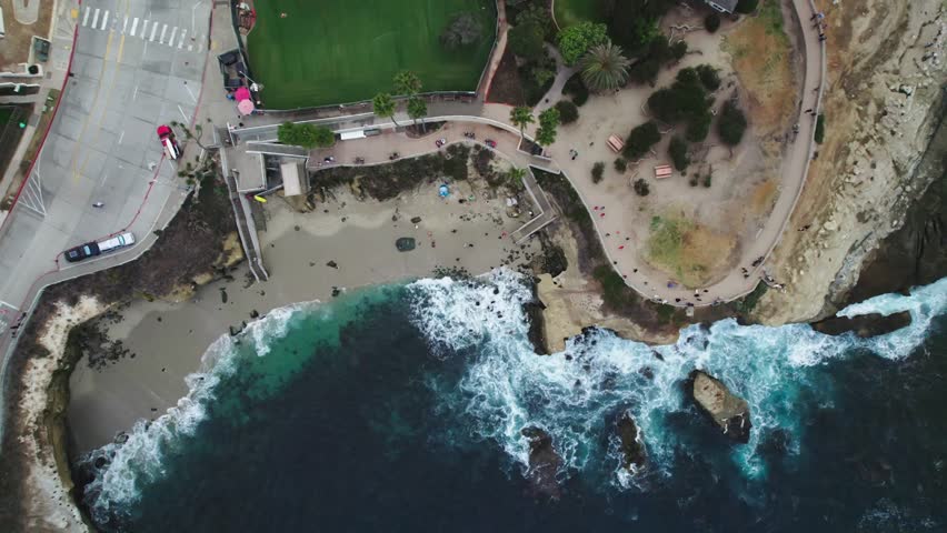 A stunning 4K aerial view of the Children's   and the surrounding coastline in La Jolla, San Diego, California, featuring the sea wall, beach, and ocean waves.