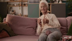 Portrait of cheerful woman gently embracing white haired elderly mother knitting on sofa in living room, expressing love and affection, slow motion - Powered by Shutterstock - Get 15% off with code: PIKWIZARD15